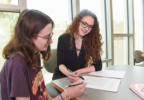 A peer writing tutor mentors a student on citing sources